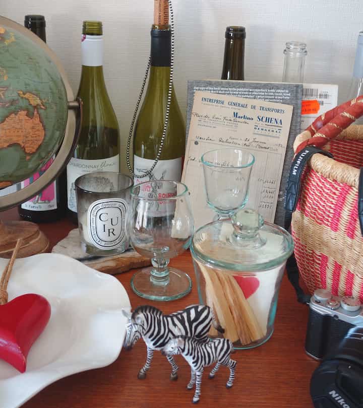 ブラウンの木目調テーブルに透明なワイングラスとキャンドル、インテリア小物が配置されたヴィンテージなダイニング空間