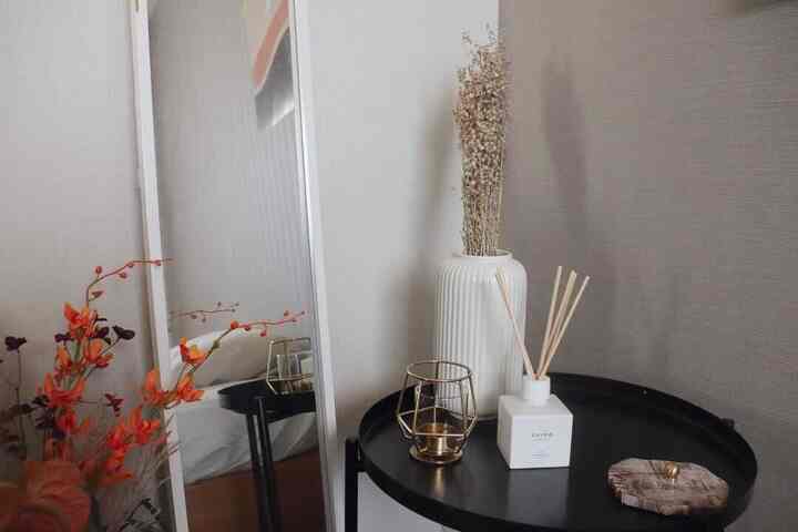 白と黒の色調が特徴の寝室、自然な雰囲気の花瓶とディフューザーを配した印象的なインテリア