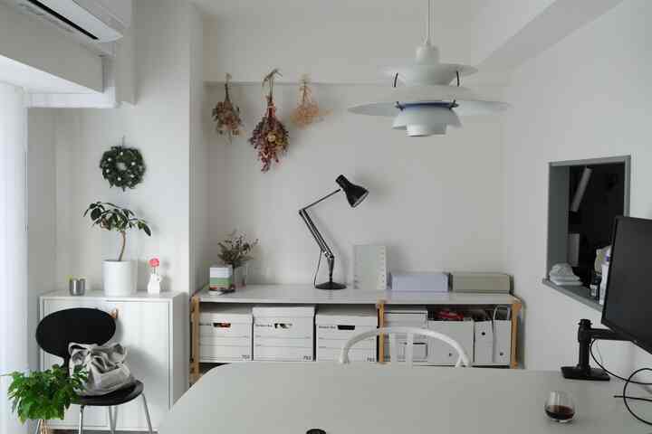 White-toned compact home office featuring organized storage boxes and minimalist furniture layout with a functional workspace