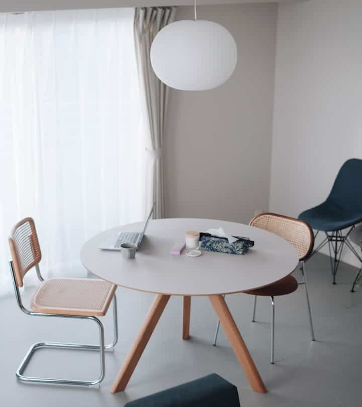 白と木目調のダイニング、モダンな家具と丸テーブルが配置された印象的な空間