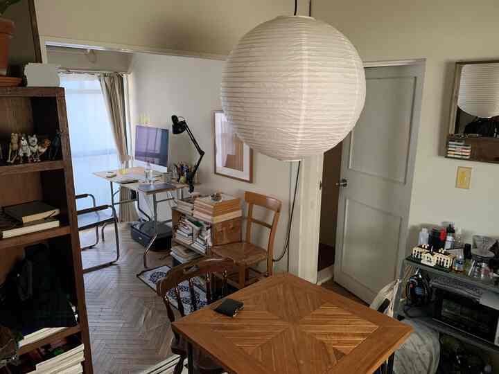 Wood tone apartment dining room with a white pendant light and home office setup