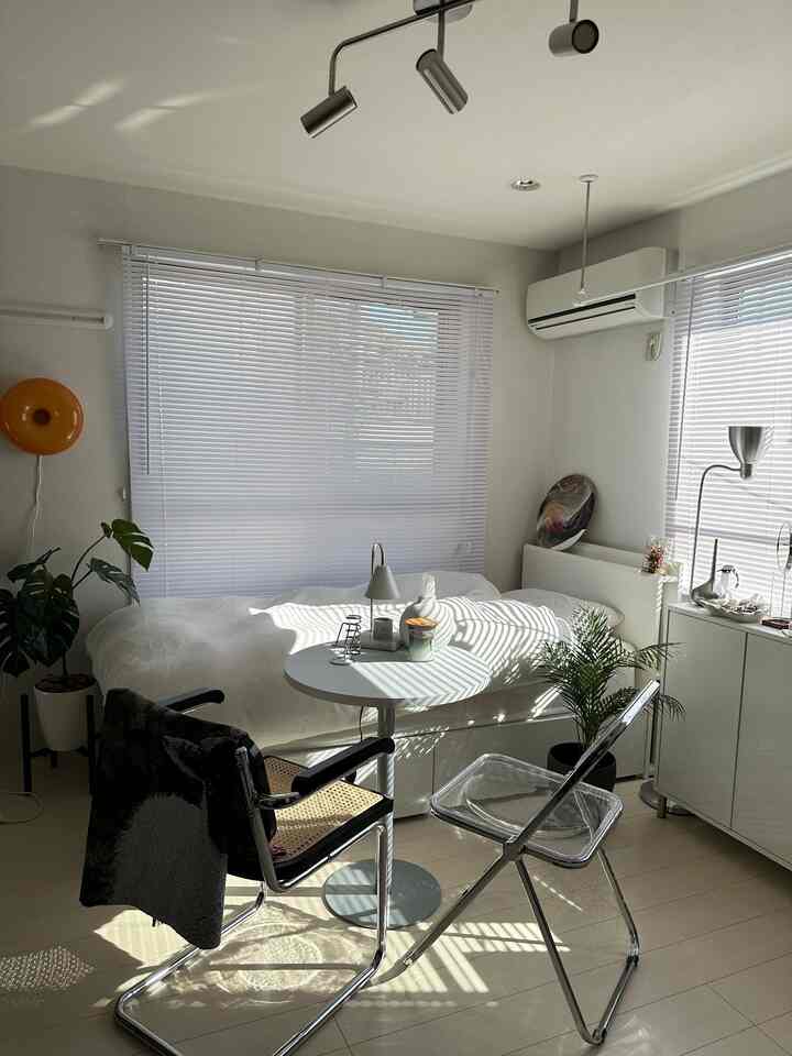 White-toned compact studio apartment with modern furniture and blinds on windows, featuring a clean and cozy atmosphere