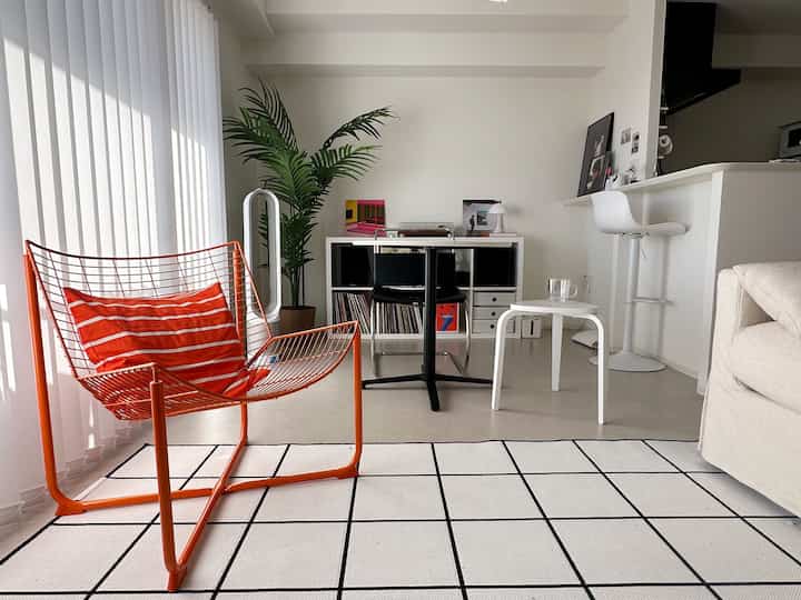 A white and orange Nordic living room featuring simple furniture and a rug with a natural atmosphere