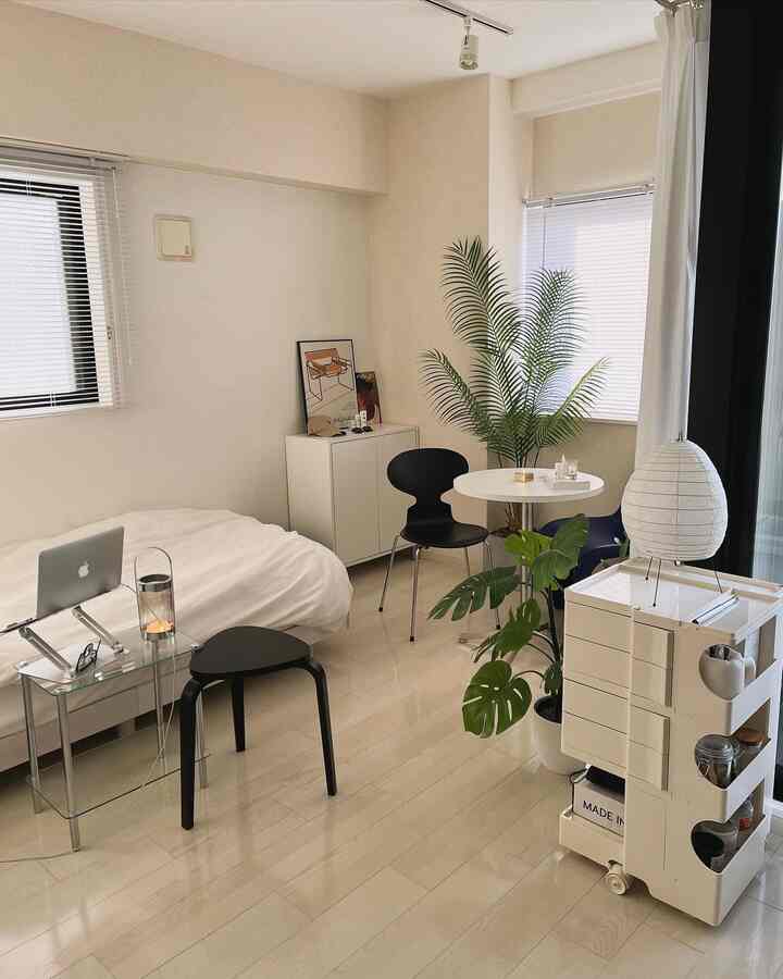 White and natural wood tone single household bedroom, featuring black chairs and stool in a neat layout
