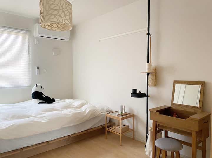 A cozy white and beige bedroom featuring a wooden bed frame and simple furniture with a natural modern atmosphere
