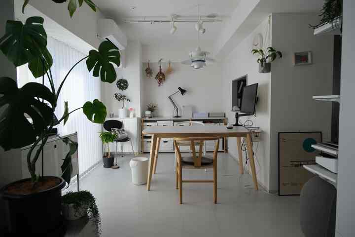 白と木目調の調和したナチュラルモダンなリビング、中央にダイニングテーブルと椅子が配置されたシンプルなホームオフィス空間