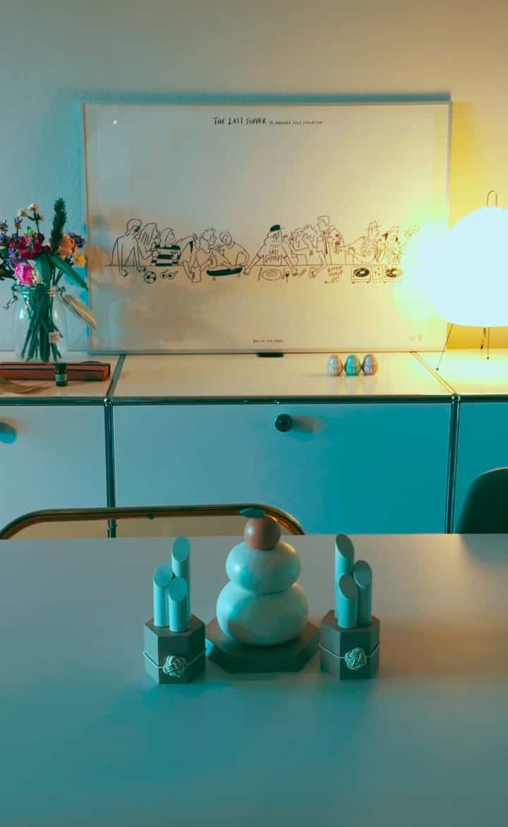 White-toned living room featuring a sideboard, floor lamp, and flower vase with a modern and clean interior style