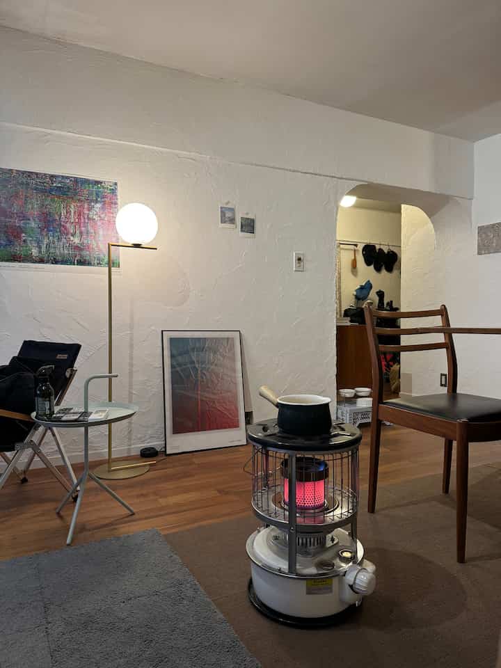 Mid-Century Modern dining room with brown wood floor and white walls, featuring a floor lamp, side table, and dog feeding bowls in a cozy setting