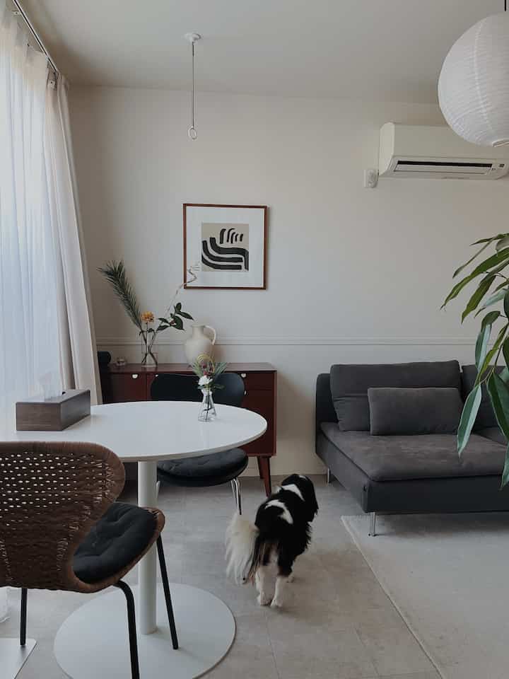 White and gray toned living room featuring a gray sofa and white dining table with a clean, natural atmosphere