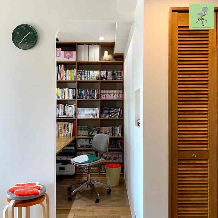 White walls and wood-tone furniture define a study featuring bookshelf and office chair in a cozy workspace