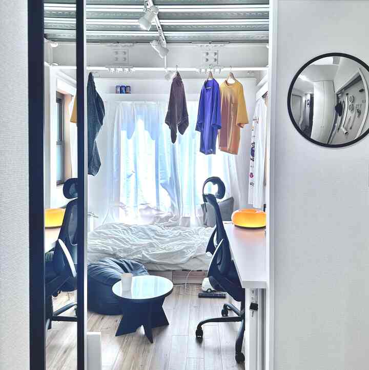 白と黒のトーンの6畳ワンルーム、シングルベッドとデスク、チェアが配置されたシンプルでミニマルな印象的な空間