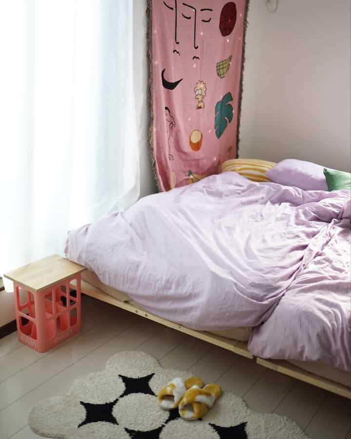 Lavender-toned bedroom featuring a wood-tone bed with natural light and cozy yellow fur slippers