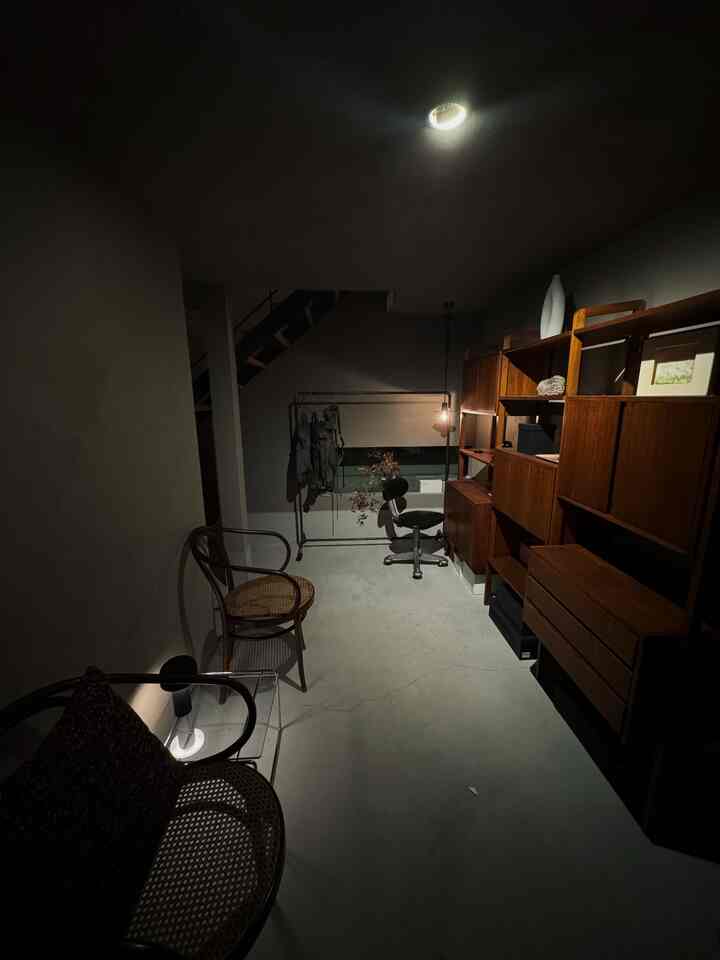 Dimly lit entrance area featuring vintage wooden cabinets and chairs with a calm atmosphere