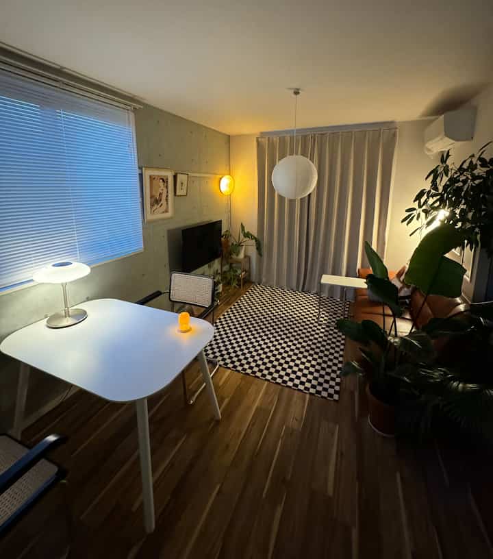 White and brown toned living room featuring checkered rug, sofa, and lamps with a cozy spacious atmosphere