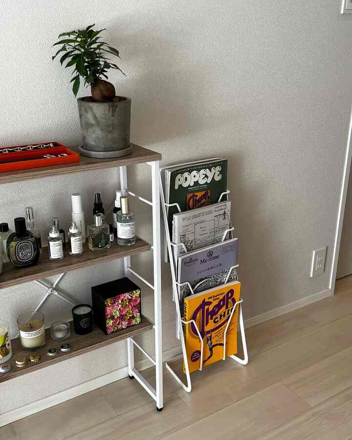 ナチュラルな色調のリビング、白いマガジンラックと木製の棚に香水と雑誌が整然と配置された、落ち着いた雰囲気のあるインテリア