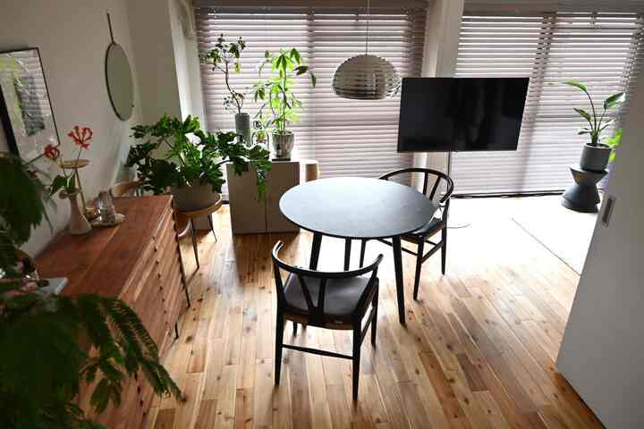 Natural wood tone flooring and dining set with sideboard and pendant light in a cozy living room space