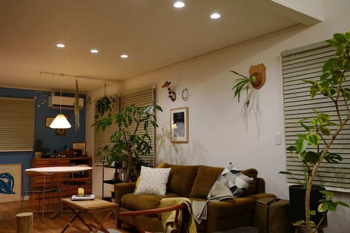 ブラウンのソファとナチュラルな木製家具、植物が配置された北欧風のリビングルーム