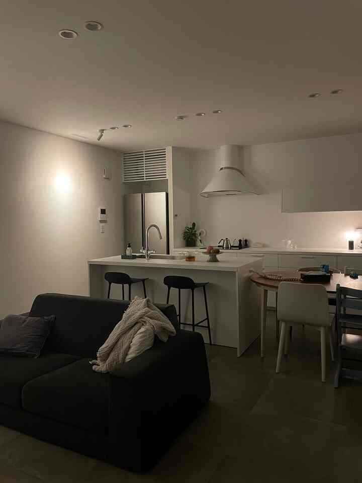 白と黒のトーンのモダンなリビングキッチンスペース、バースツールやダイニングテーブル、落ち着いた雰囲気のインテリア