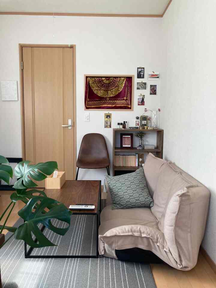 Natural wood tone compact single household living room featuring beige floor sofa, brown leather dining chair, and gray rug with a simple atmosphere