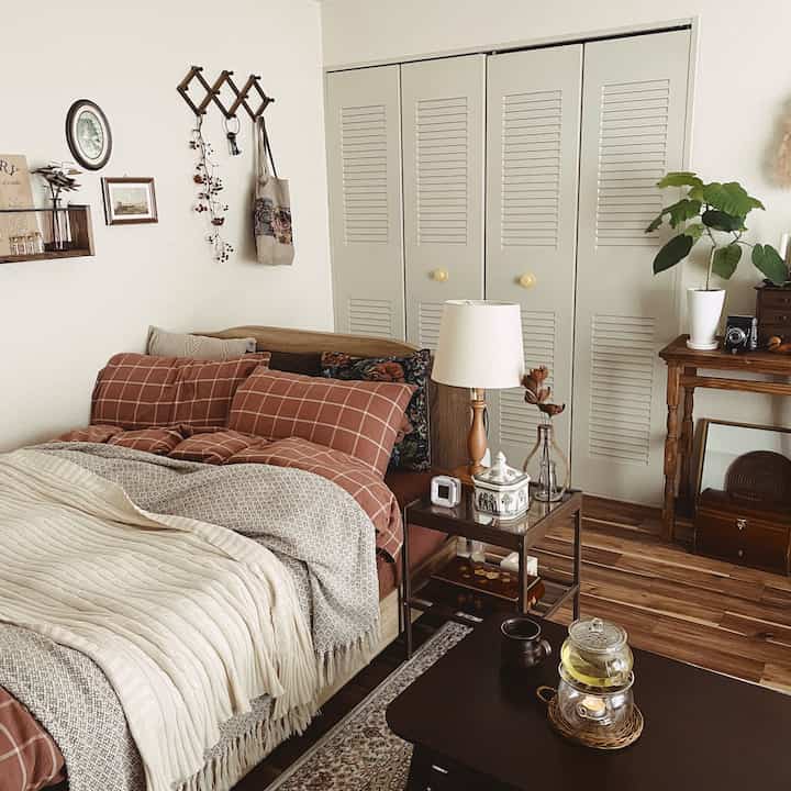 ナチュラルな色調の寝室、木製ベッドとナイトテーブル、ヴィンテージの小物が配置された雰囲気のあるインテリア