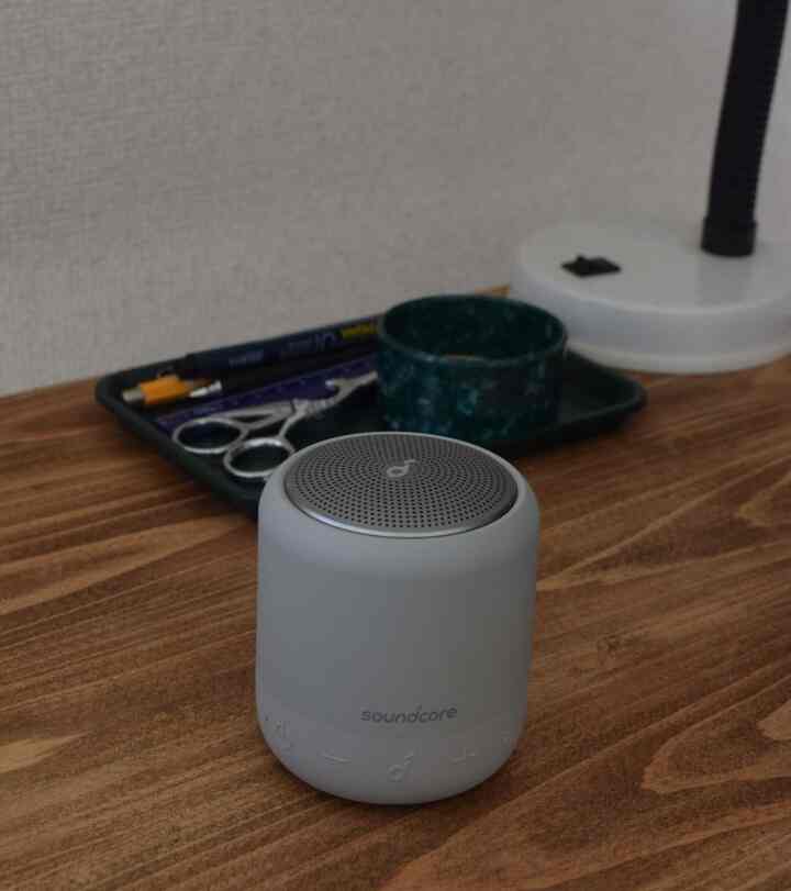 ナチュラルな木目調のデスクに白いテーブルランプと青色の小物が配置されたシンプルな空間