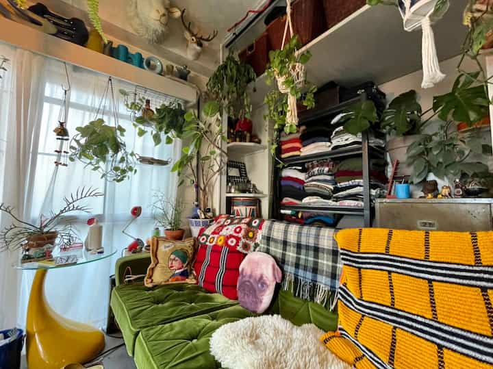 グリーンベルベットのソファと豊富な観葉植物が配置されたヴィンテージ感のあるリビング空間