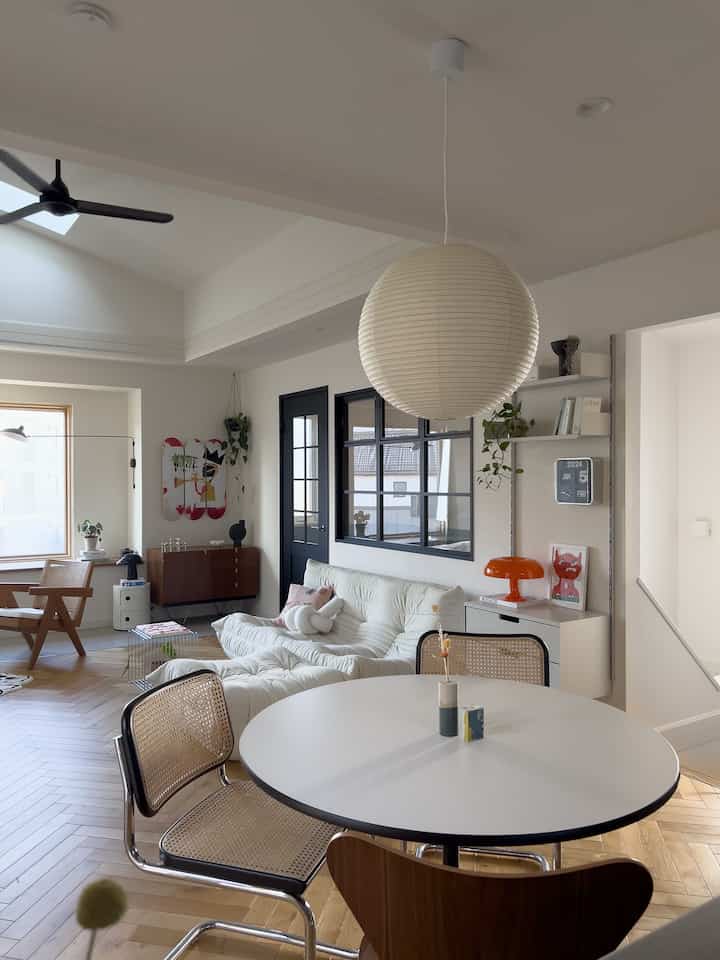 Mid-Century Modern dining and living room featuring white and wood tones with natural light and stylish furniture