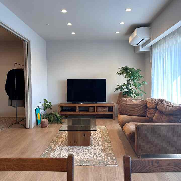 Cozy two-person living room with natural wood tones and brown sofa under soft natural light