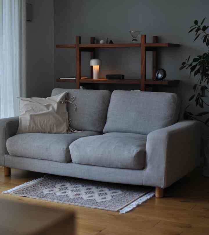 グレーのソファと木目調の棚が配置されたナチュラルな雰囲気のリビングルーム