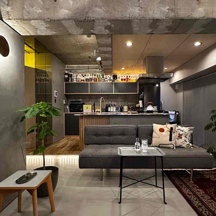 グレーのソファと木目調の床が調和するナチュラルモダンなリノベーションのリビングキッチン、ホームバーが印象的な空間