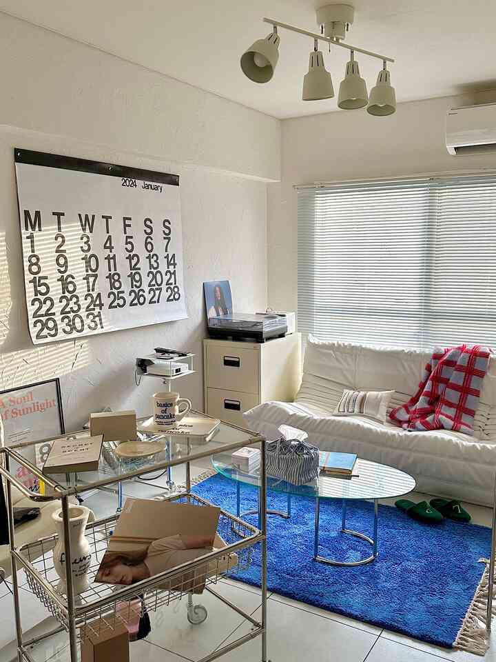 明るいホワイト調のリビングルーム、モジュール家具のトロリーと白いソファが配置された印象的で広々としたインテリア