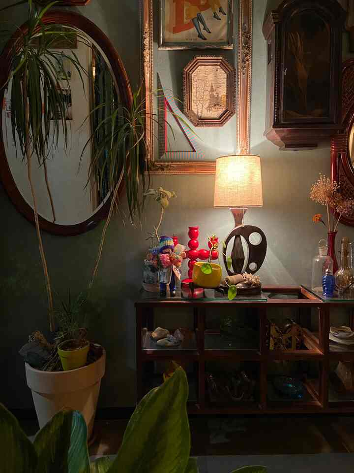 緑の植物と赤いキャンドルスタンドが配置されたミッドセンチュリーモダンのリビング、ヴィンテージで温かみのある雰囲気