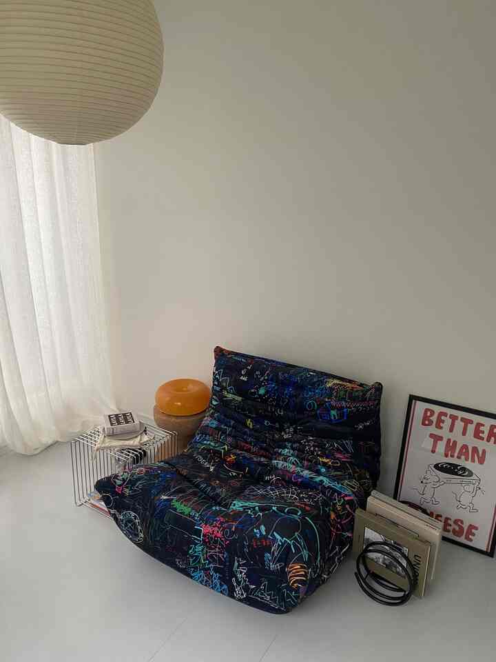 白を基調としたモダンでシンプルなリビング、色鮮やかなパターンのソファが印象的な空間