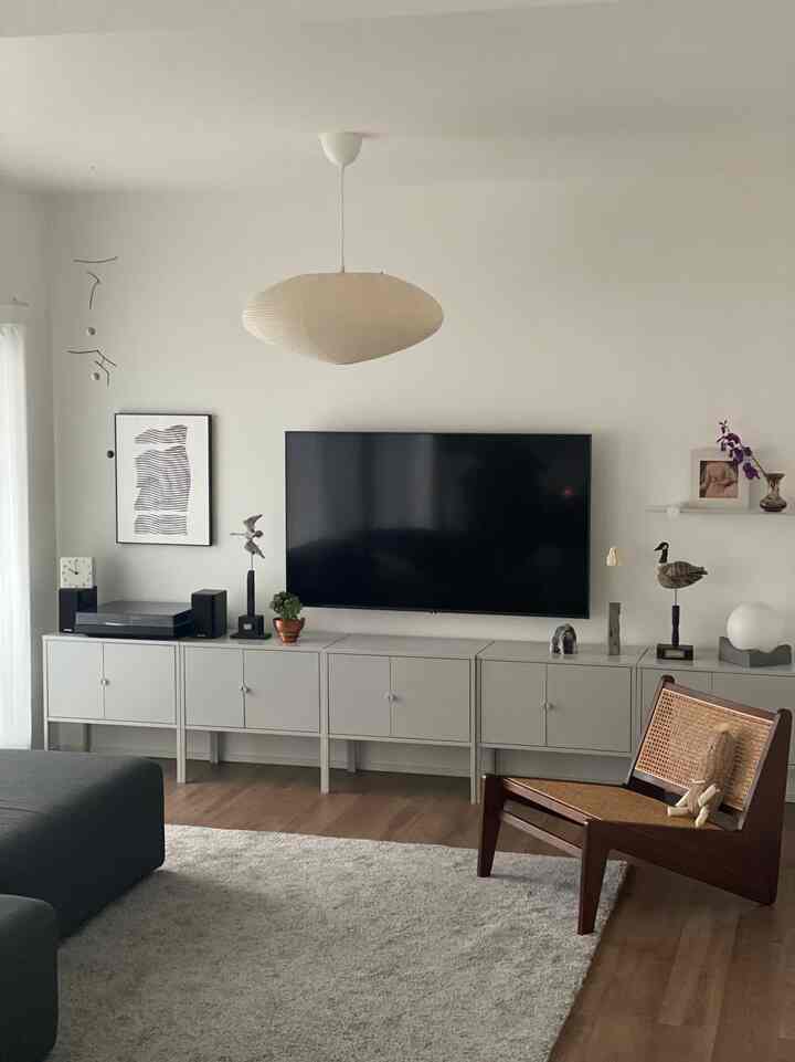 White and gray toned living room featuring a TV stand and wooden armchair in a simple, natural setting