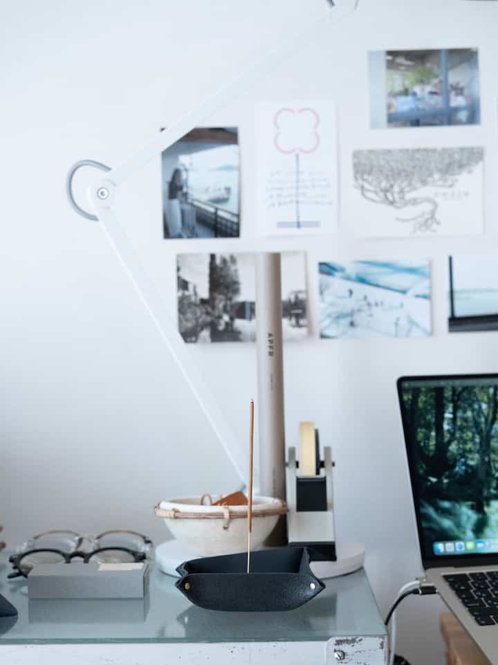 White-toned home office space featuring glass desk with incense stick on black tray, conveying a simple atmosphere