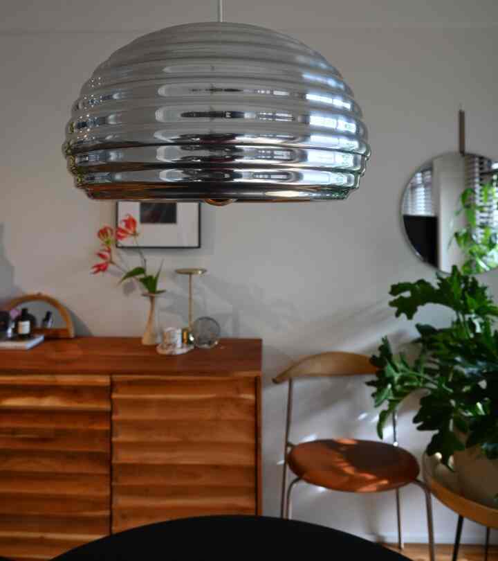 シルバーペンダントライトが印象的な北欧風リビング、木製のサイドボードと丸い鏡が配置された落ち着いた空間