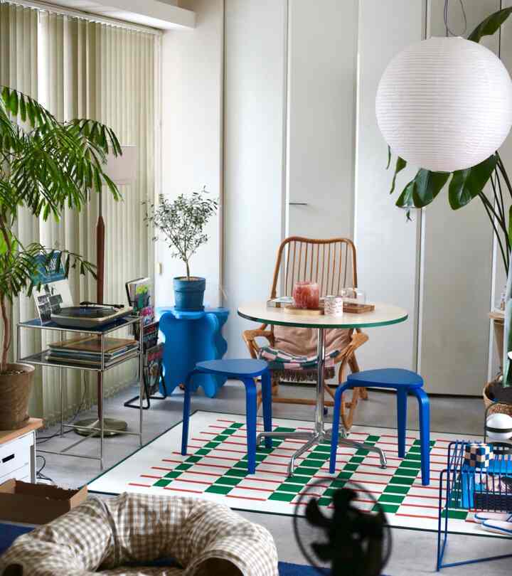 ナチュラルな雰囲気のホームオフィス、ミッドセンチュリーの丸テーブルと青いスツールが配置された居心地の良い作業スペース