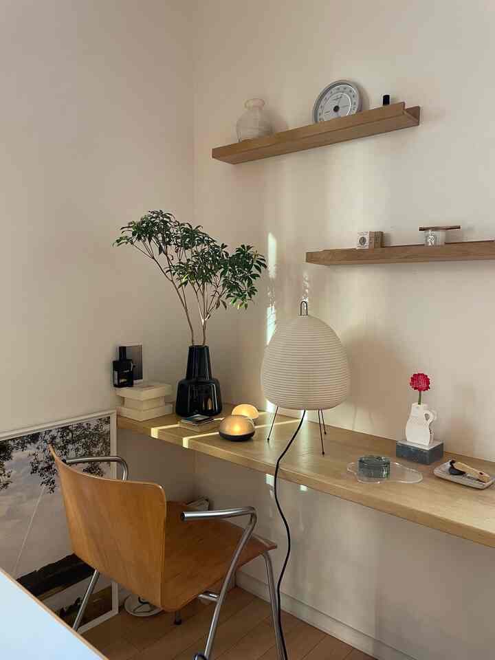 Natural and minimal toned home office featuring wood-tone desk and chair, candles, and plants with a calm atmosphere