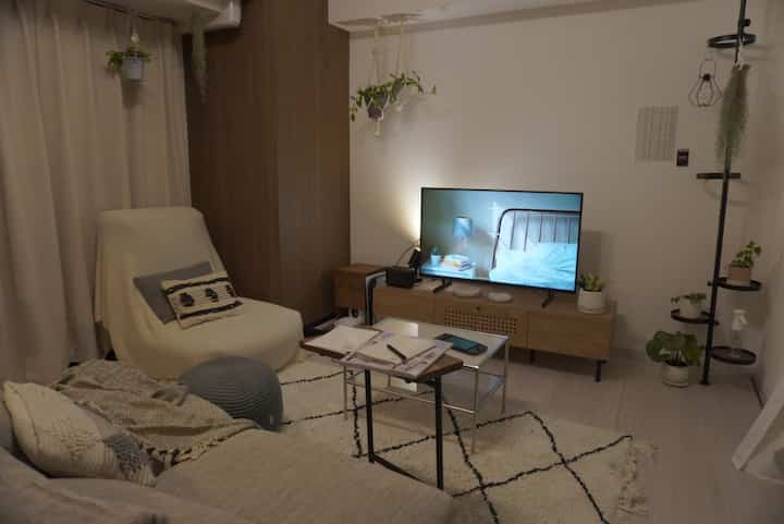 Natural color and brown toned 1LDK living room featuring sofa and TV stand with cozy ambient lighting