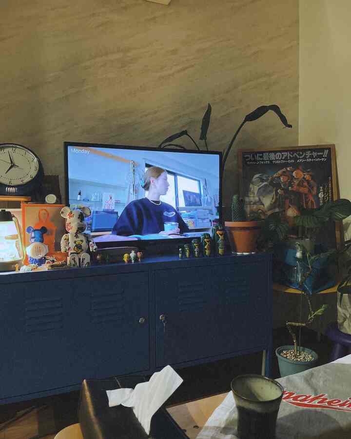 ベージュの壁と青いキャビネットが配置されたリビング、テレビと植物がある落ち着いたモダンな雰囲気のインテリア