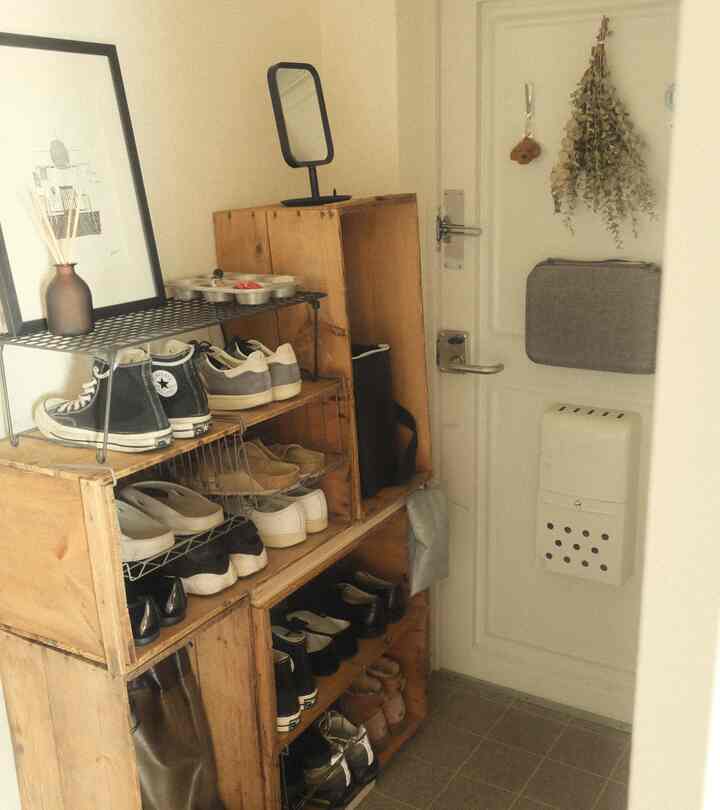 白い壁と木目調のシューズラックが配置された狭い玄関スペース