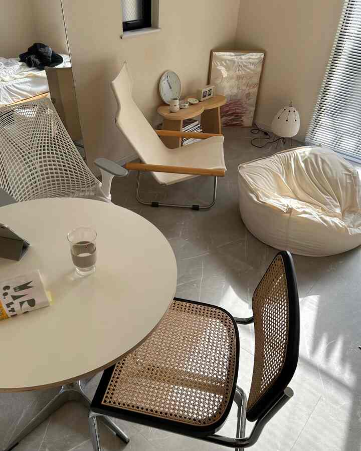 ナチュラルな色調の小さなリビング、円形テーブルとアームチェア、ビーズクッションが配置されたシンプルな空間