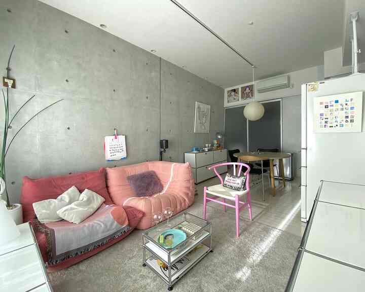 ピンクとグレーのトーンが調和したリビング、ピンクのソファとYチェアが配置され落ち着いた雰囲気の空間