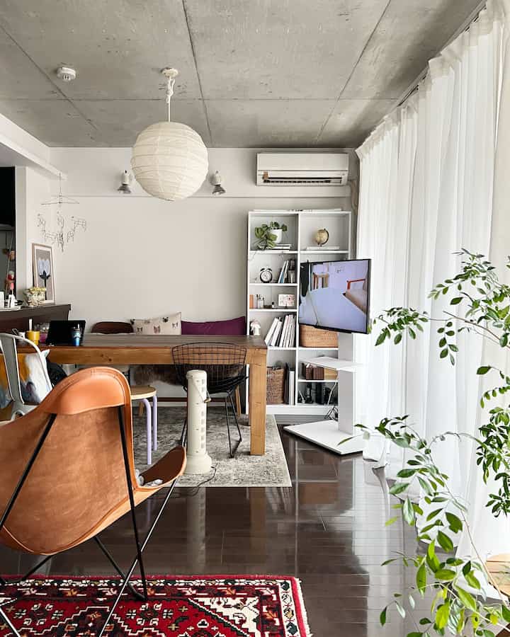 白と木目調が調和した一人暮らし向けの1LDKリビング、キャスター付きのテレビ台と自然なダイニングテーブルが配置されたモダンでナチュラルな空間