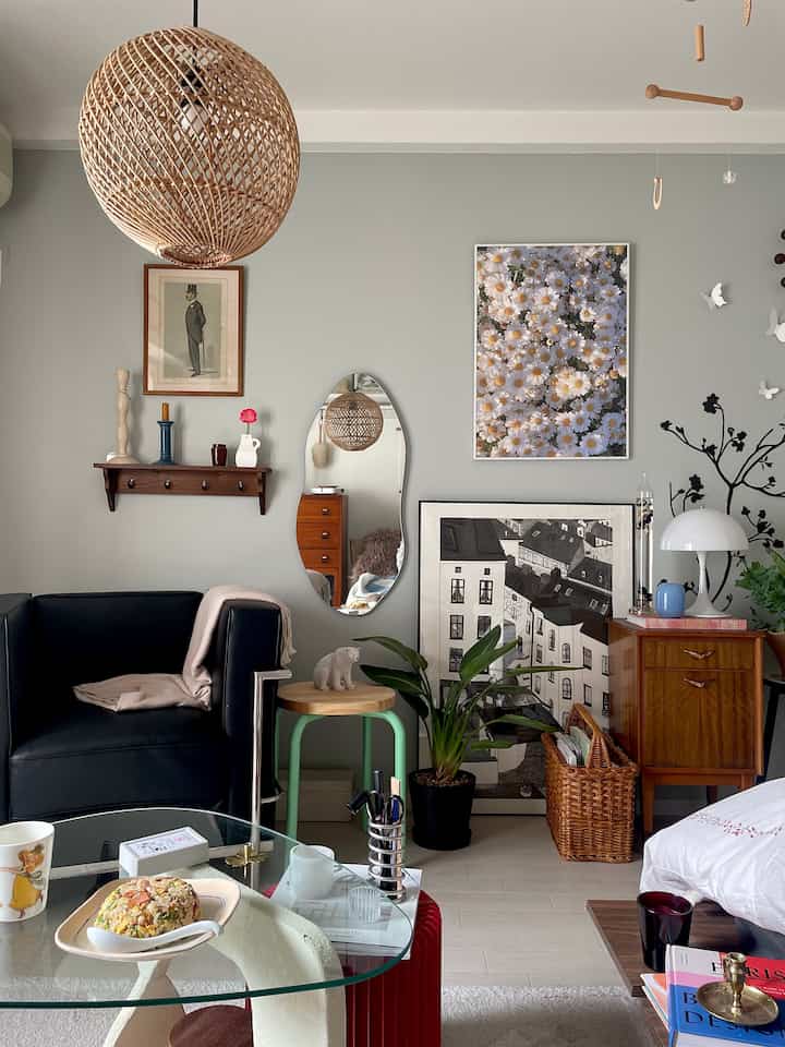 Gray walled living room featuring natural wood furniture, black armchair, and glass coffee table creating a cozy atmosphere