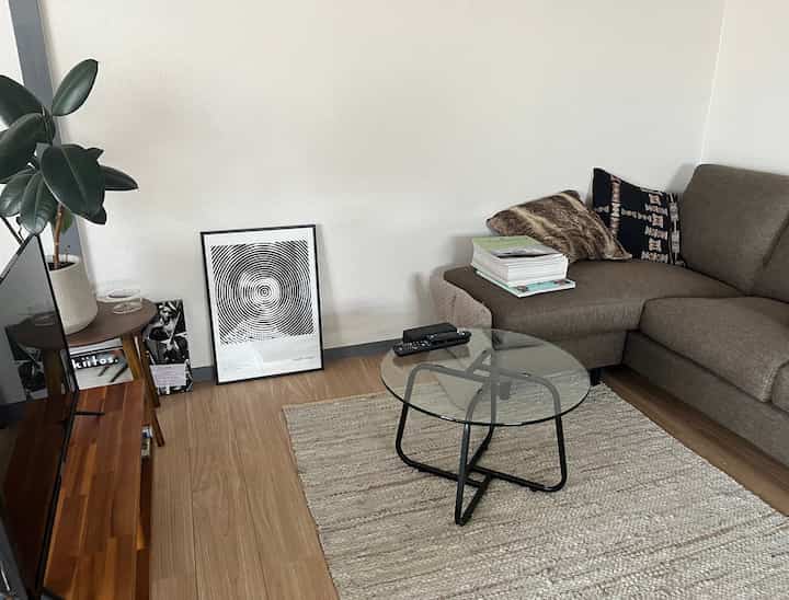 ブラウンとナチュラルカラーのリビング、中央にガラスのローテーブルとゆったりとしたソファが配置された落ち着きのあるインテリア