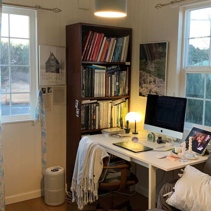 White and brown toned compact home office featuring a bookshelf and modern desk setup