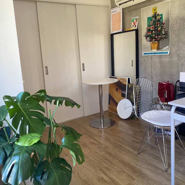 白と木目調が調和したモダンなリビングルーム、丸いダイニングテーブルとワイヤーチェア、大きなモンステラが配置された空間