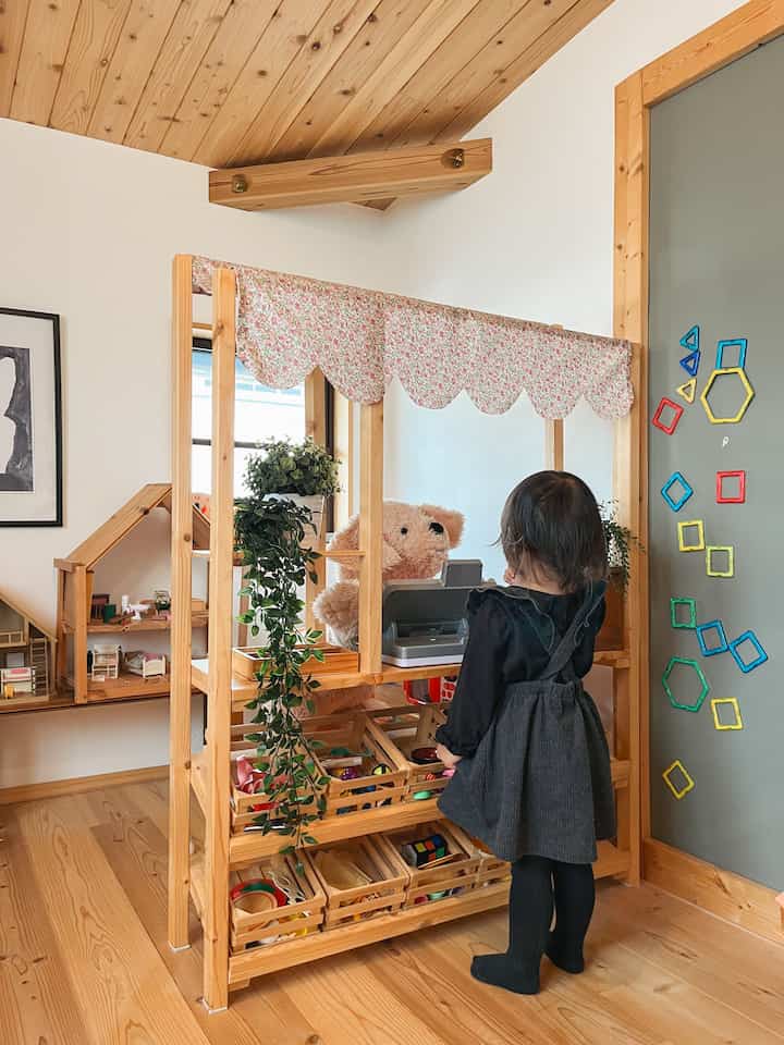 明るい木目調と白い壁の子供部屋、おもちゃ収納が配置された温かみのある雰囲気のインテリア