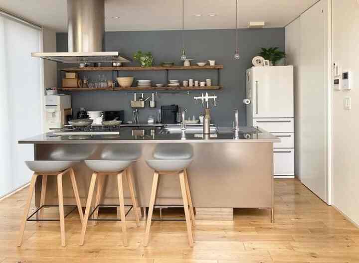 A modern kitchen featuring wood tones and white, with a kitchen island and gray stools in a simple layout